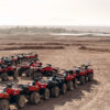 Large column of ATVs and buggies stands in the middle of a sandy desert. Ready for fun in the desert